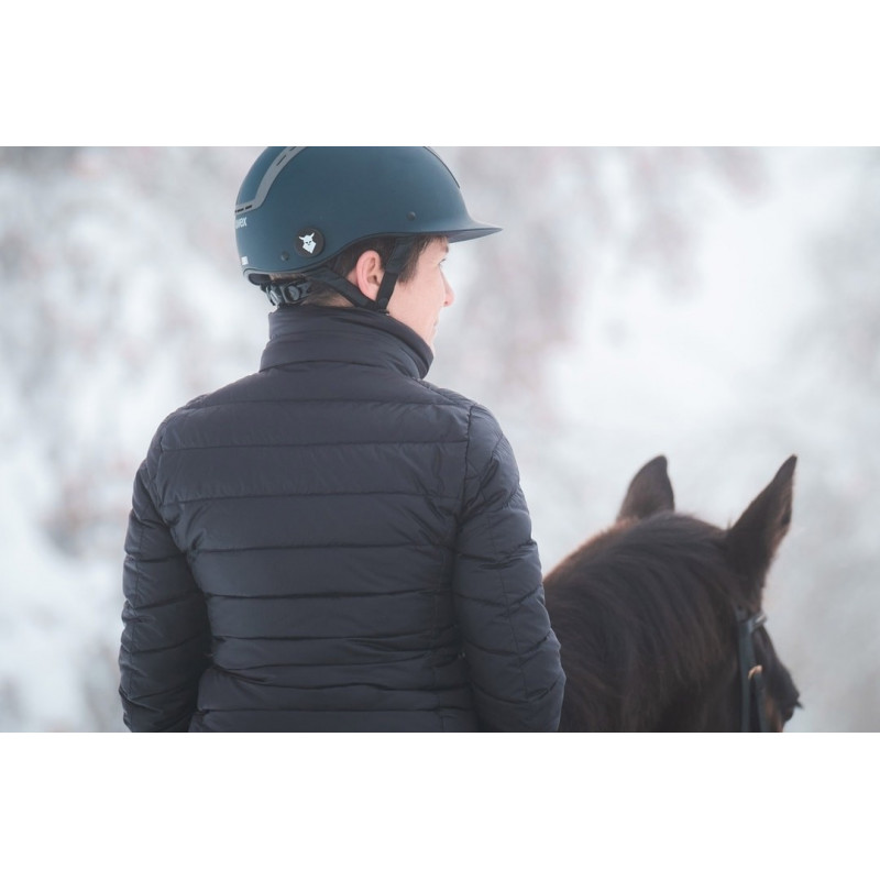 Pessoa com capacete e casaco preto montada num cavalo castanho