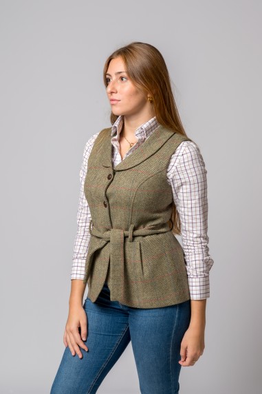 Mulher a usar colete tweed verde com padrão xadrez e camisa branca com linhas castanhas.