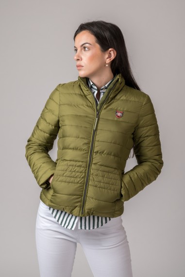 Casaco verde-oliva acolchoado com fecho e bolso usado por mulher com camisa às riscas e calças brancas