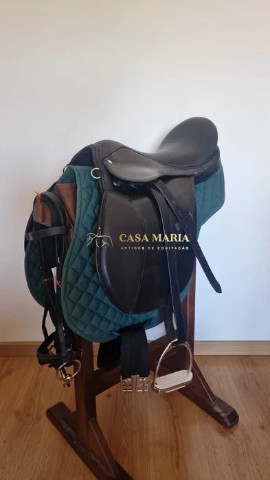 Sela de equitação preta sobre almofada verde em suporte de madeira