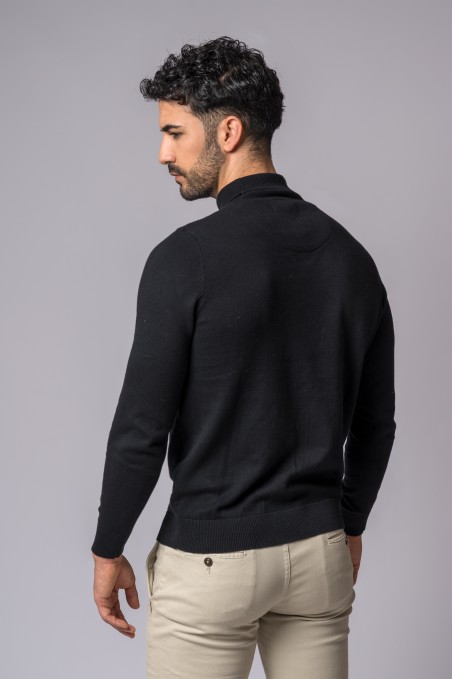 Homem com camisola preta de manga comprida e calças bege claro visto de costas