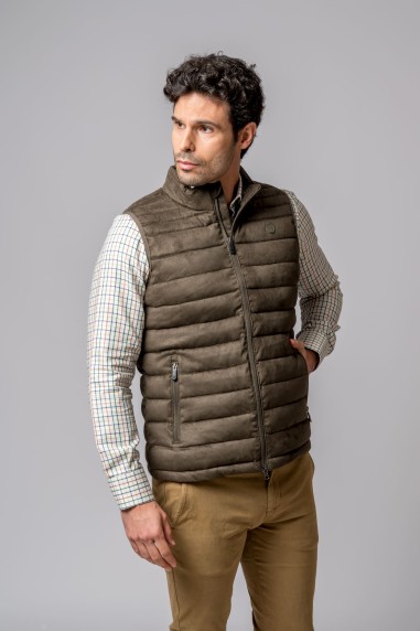 Homem com colete acolchoado castanho, camisa xadrez e calças castanhas