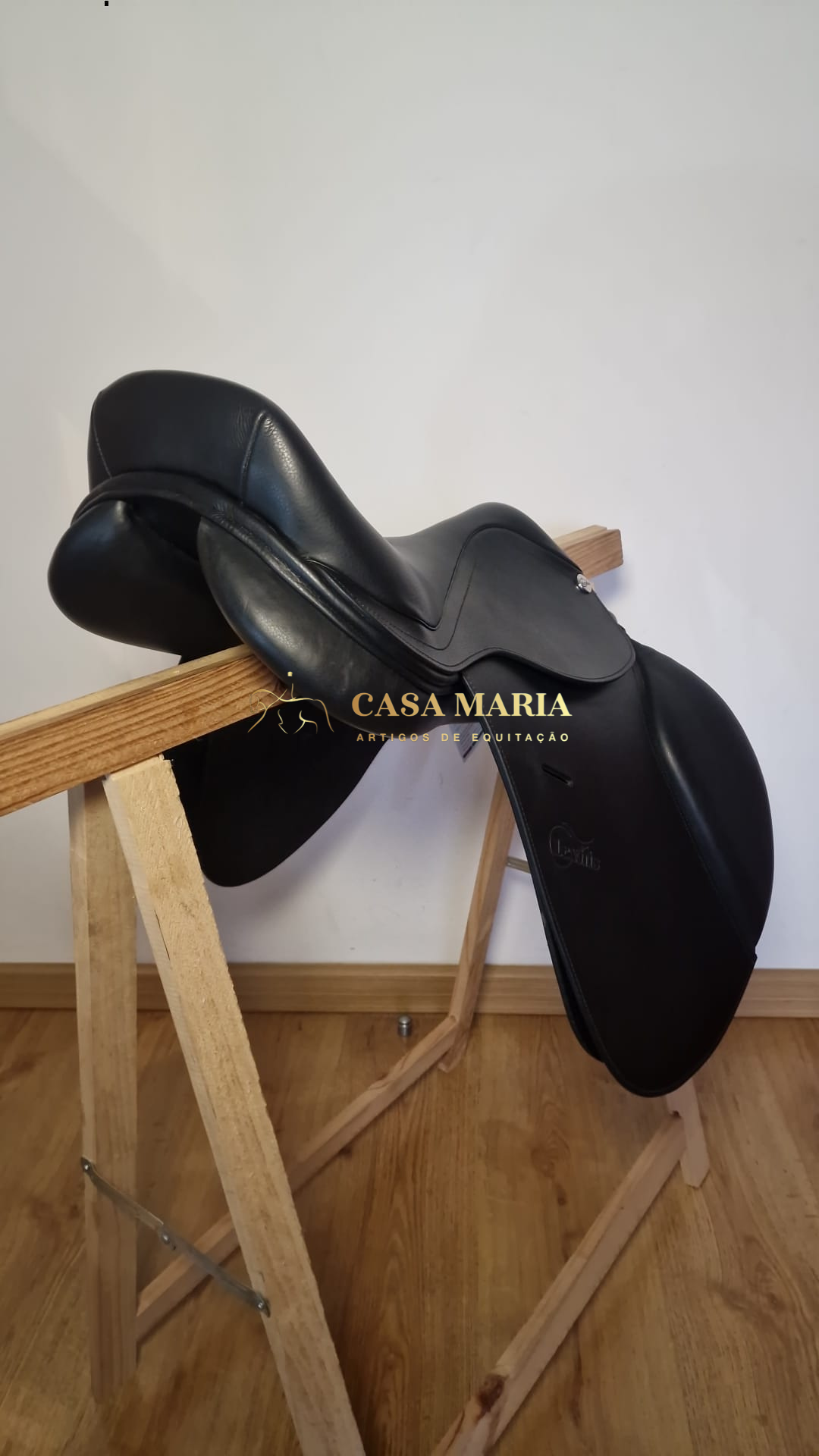 Sela de equitação preta em couro sobre suporte de madeira