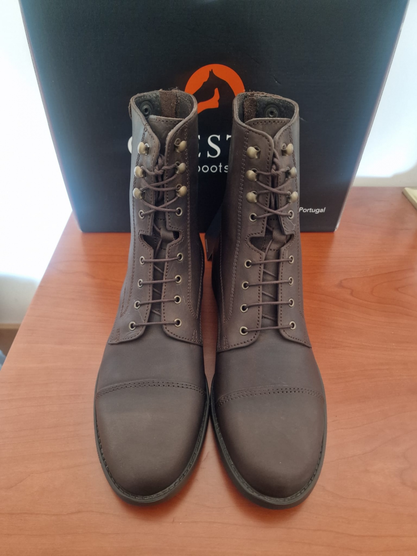 Botas de cano alto castanhas em couro com atacadores e caixa ao fundo