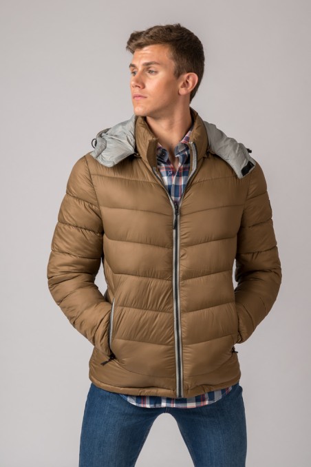 Casaco acolchoado castanho com capuz cinzento e fecho de correr, camisa xadrez e jeans azuis