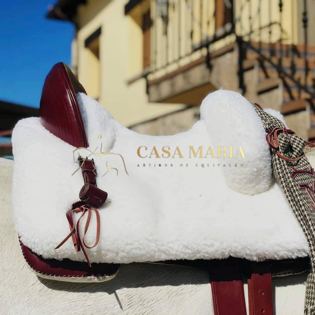 Sela branca peluda com detalhes em couro vermelho e texto CASA MARIA EQUINO DE EQUITAÇÃO.
