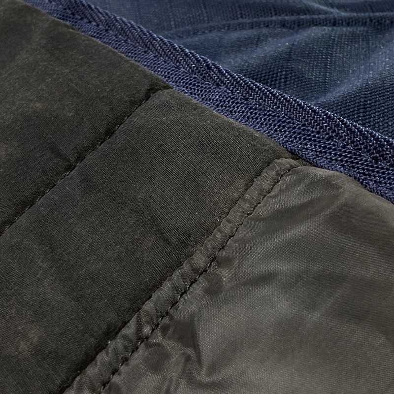 Detalhe de tecido preto e azul com costuras distintas