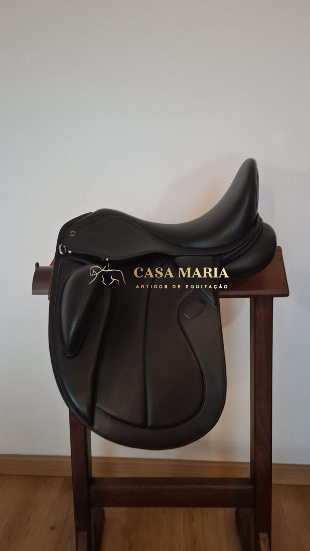 Sela de equitação preta em pele sobre suporte de madeira