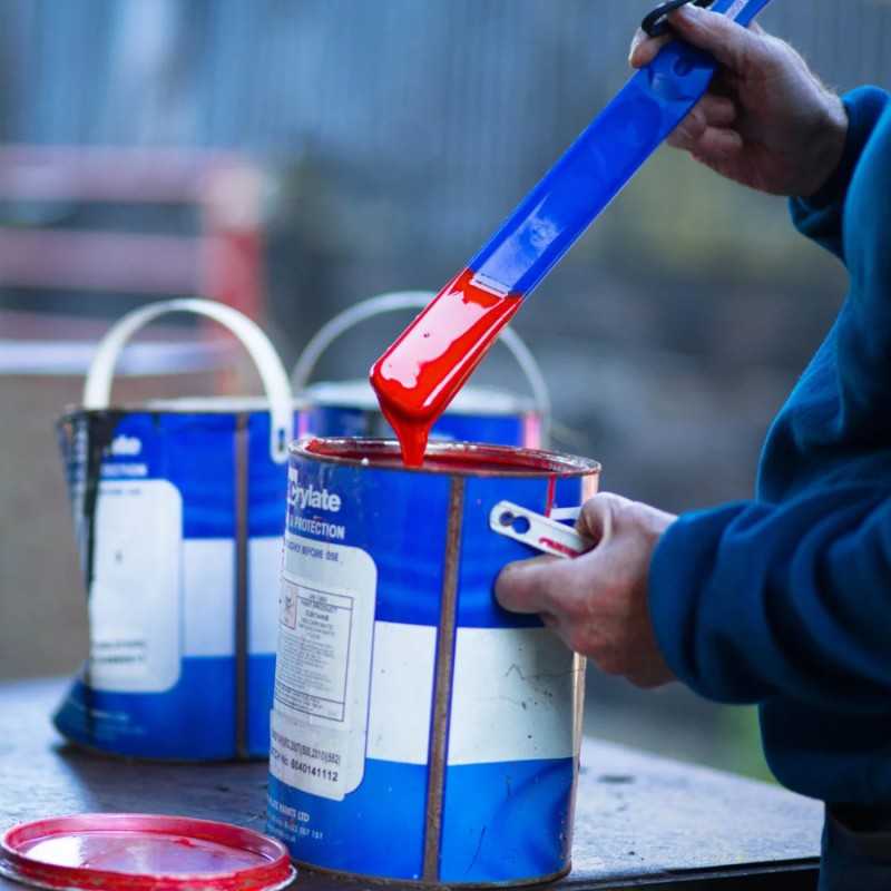 Lata azul de tinta vermelha com etiqueta branca e azul e espátula azul