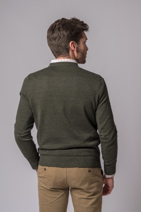 Homem de costas com camisola verde e camisa xadrez com calças bege