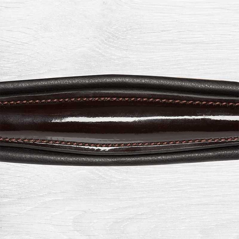 Alça de couro preto com costura cor-de-rosa sobre fundo de madeira clara