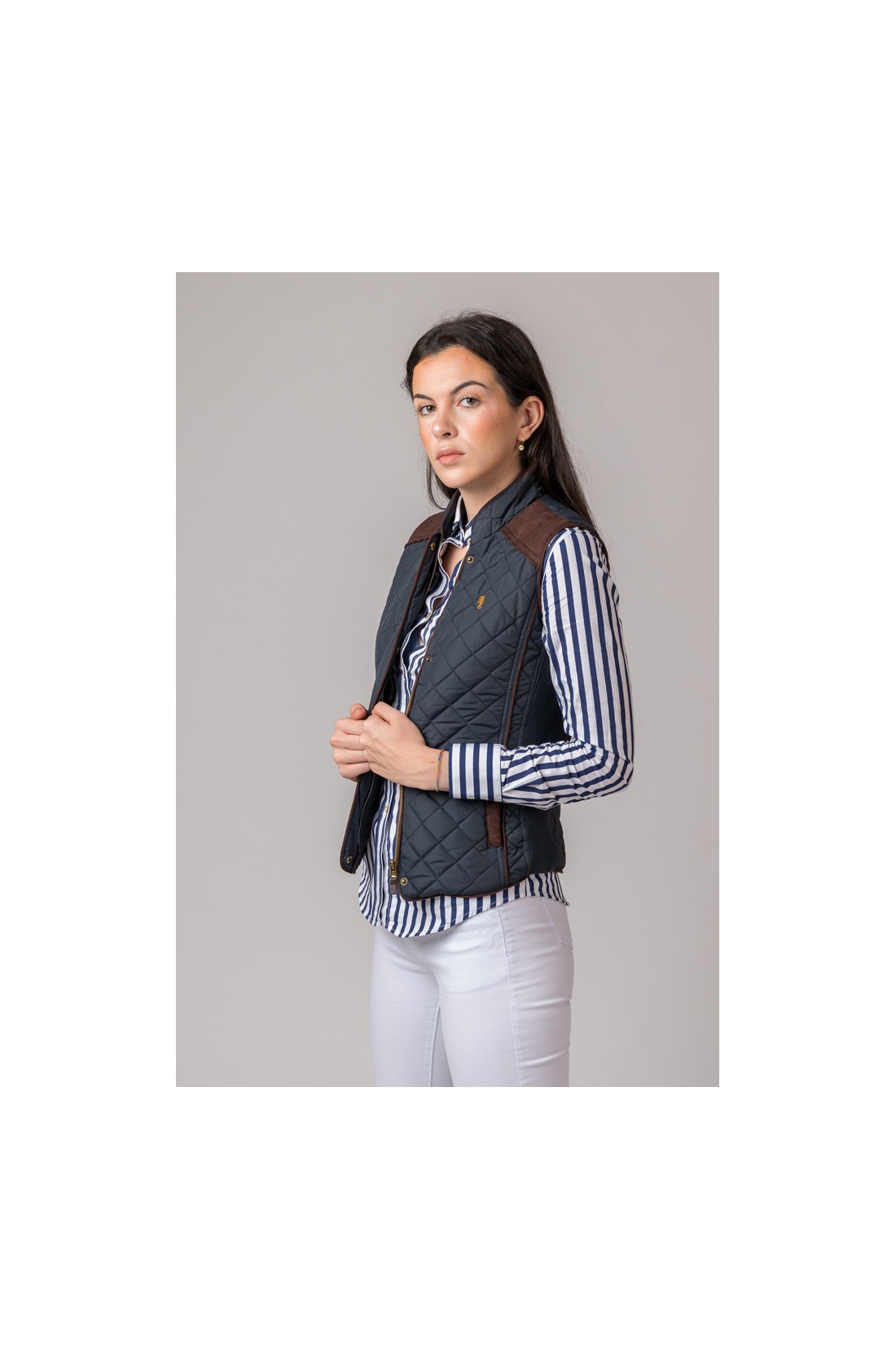 Colete azul escuro acolchoado com detalhes castanhos em modelo feminino