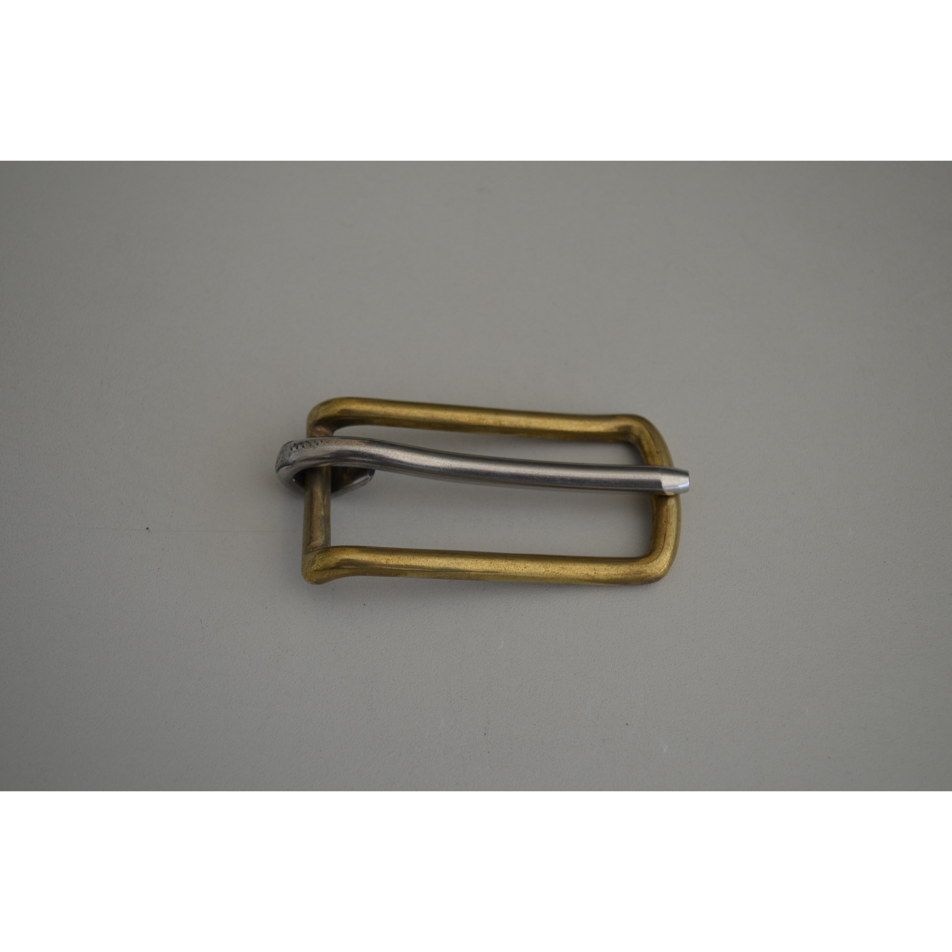 Fivela de metal dourada e prateada sobre fundo cinza