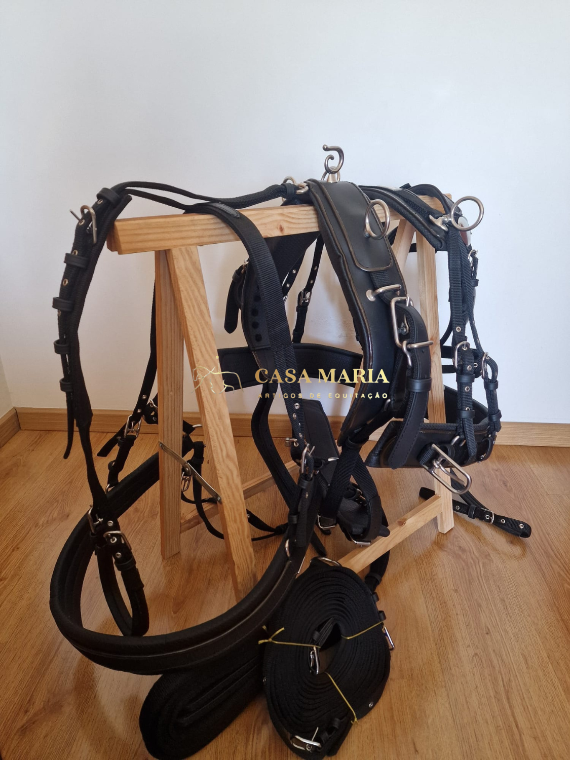 Conjunto de arreios de montaria em couro preto e nylon sobre estrutura de madeira