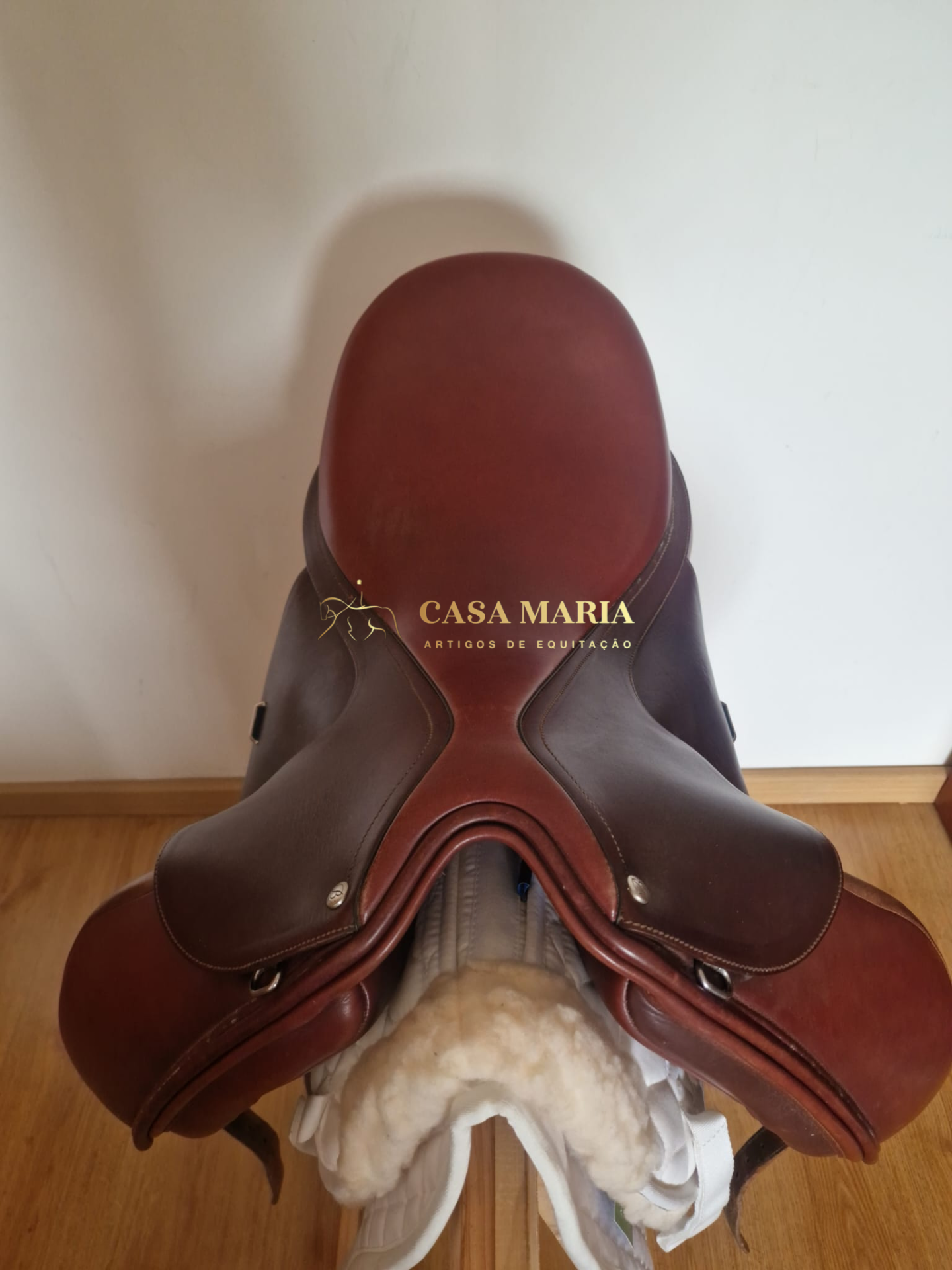 Sela de equitação em couro castanho com texto CASA MARIA ARTIGOS DE EQUITAÇÃO