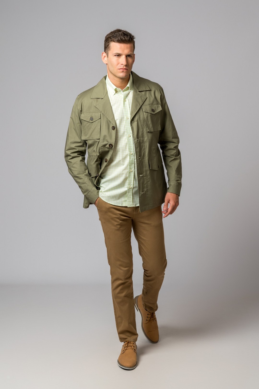 Homem vestido com casaco verde militar, camisa verde clara xadrez e calças castanhas