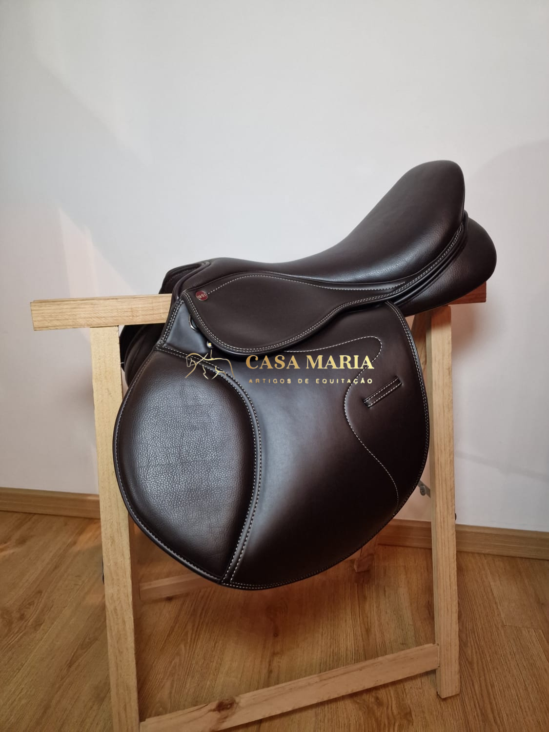 Sela de equitação castanha em suporte de madeira com marca CASA MARIA