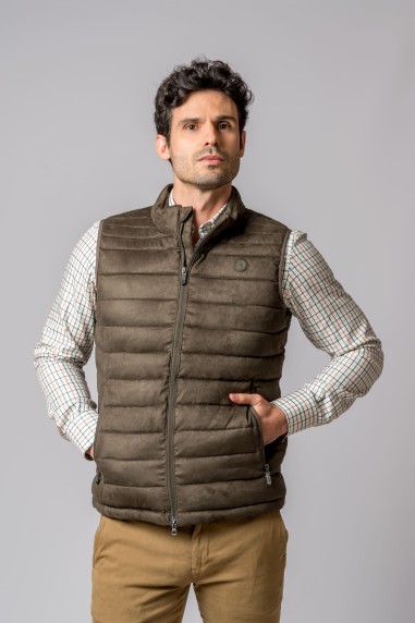 Colete acolchoado castanho com fecho, usado com camisa aos quadrados e calças bege