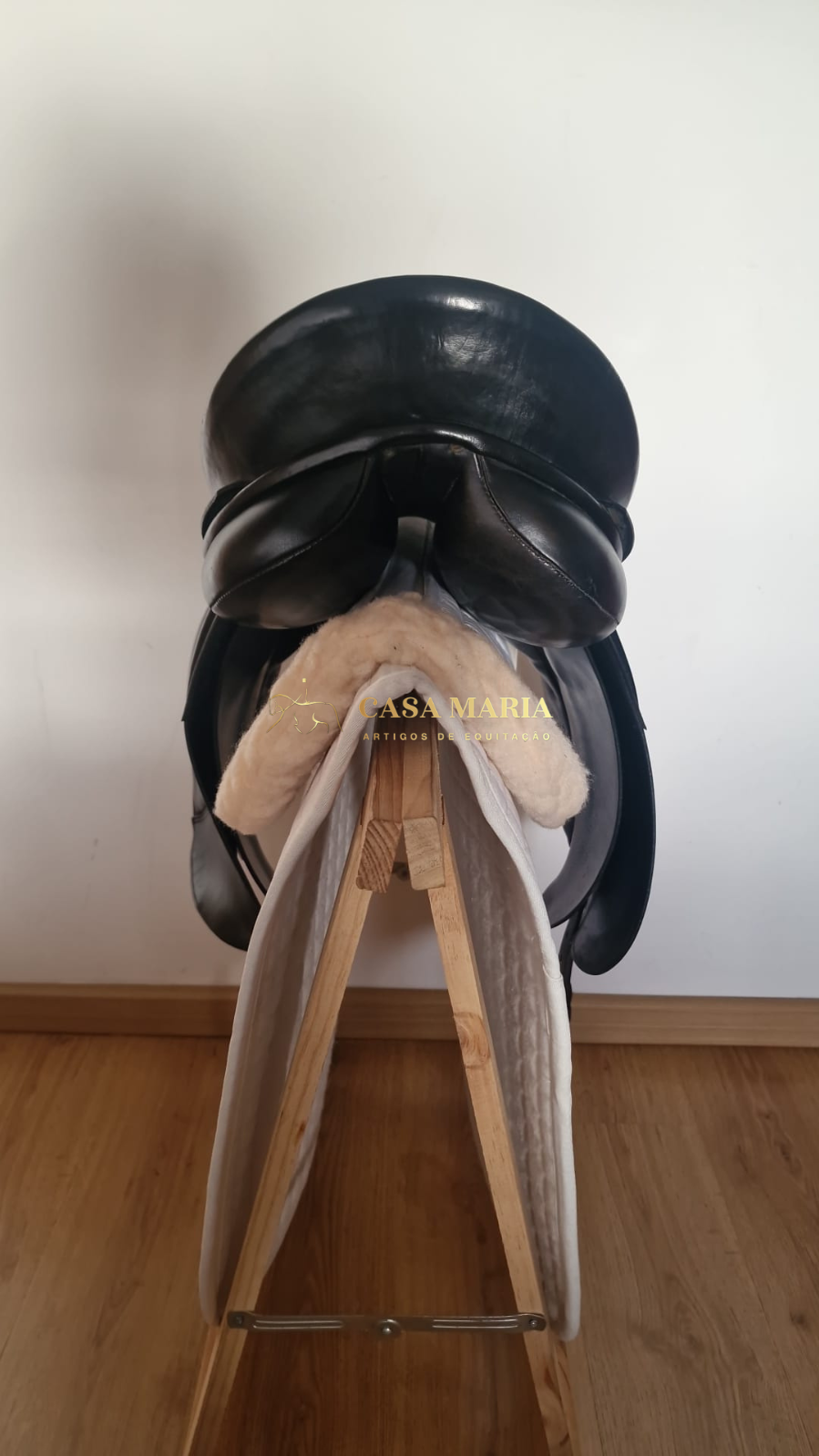 Sela preta de couro em suporte de madeira com forro branco felpudo e manta acolchoada branca
