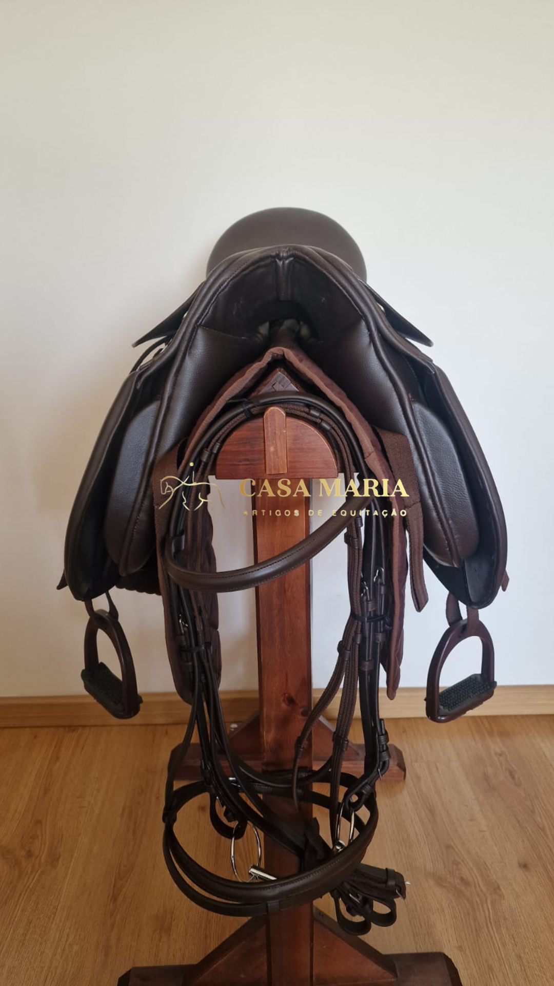 Sela de equitação castanha escura em suporte de madeira