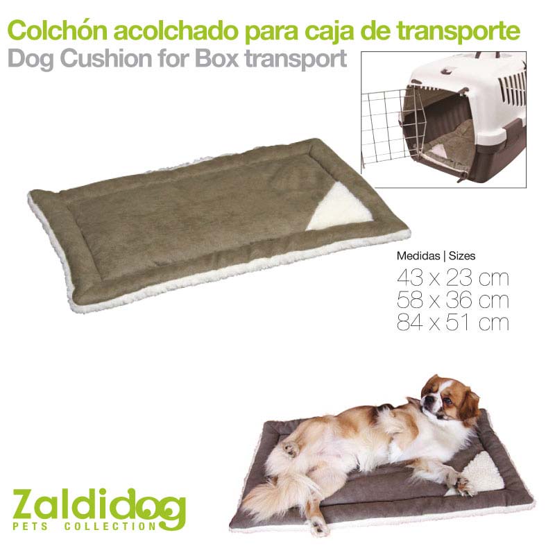 Colchão acolchoado castanho e branco para cães com cão deitado e caixa de transporte ao fundo