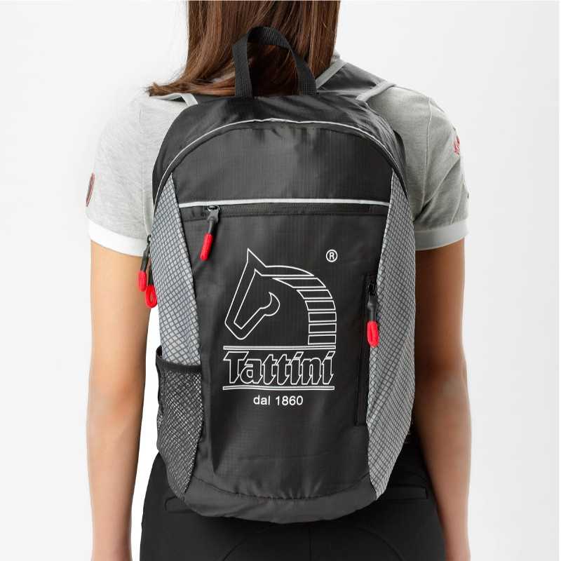 Mochila preta Tattini com logo de cavalo e texto, usada por pessoa vestindo t-shirt cinza
