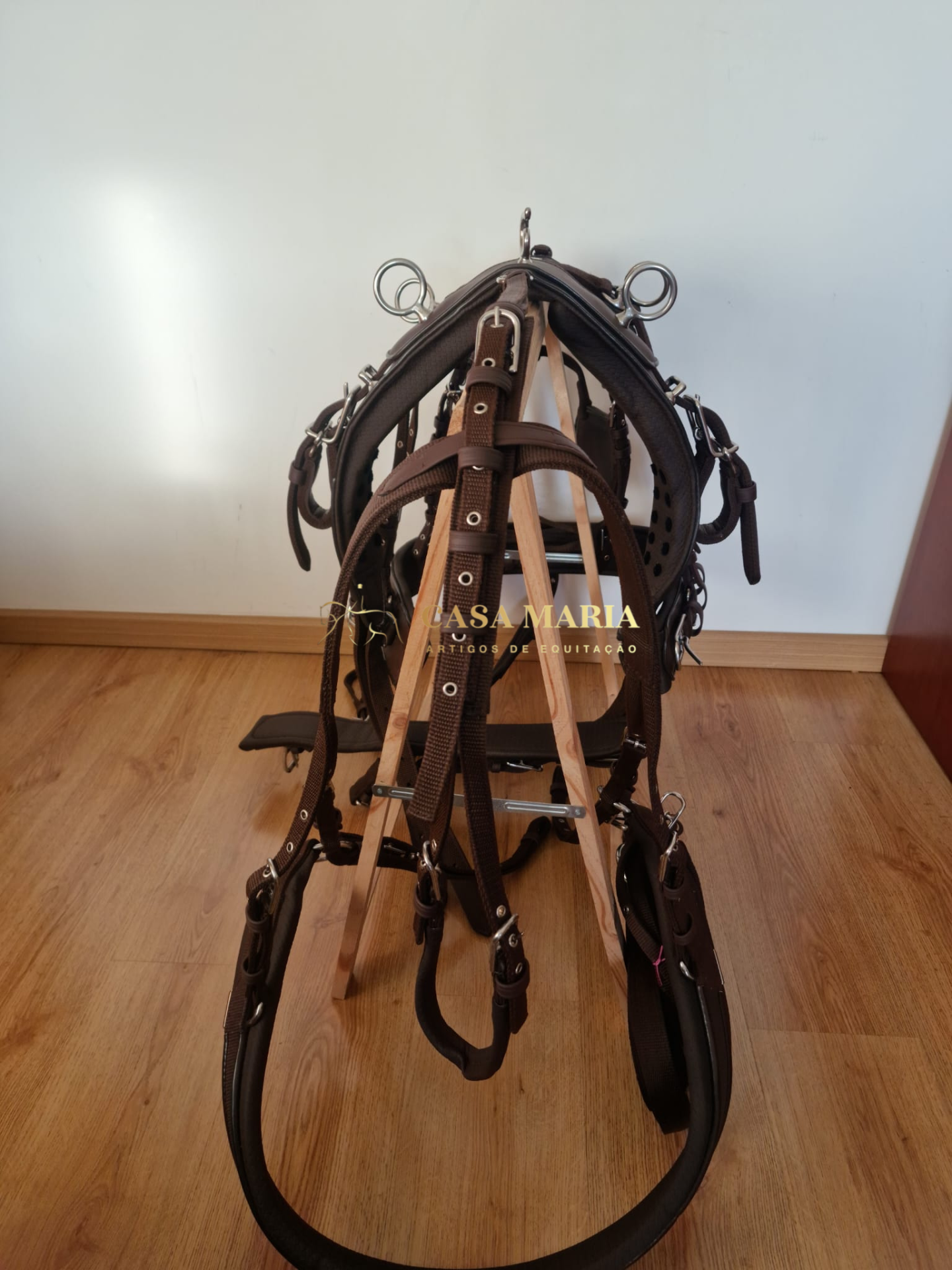 Conjunto de cabresto e rédeas em pele castanha pendurado num suporte de madeira