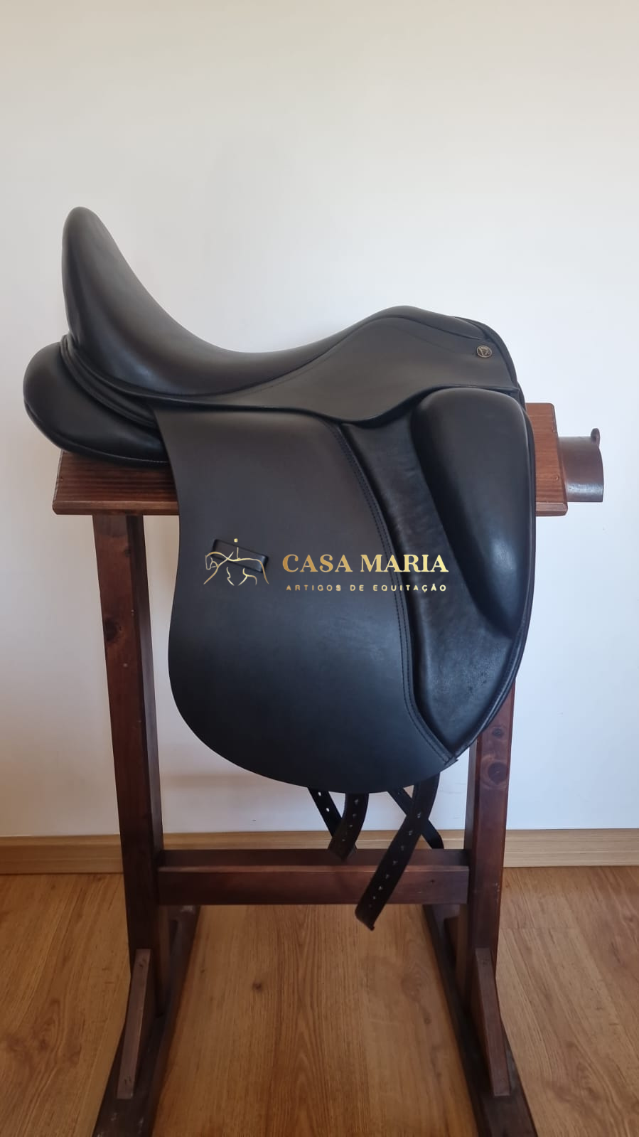 Sela de equitação preta em couro num suporte de madeira