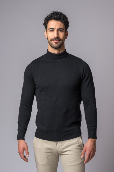 Homem com camisola preta de gola alta e calças bege claras