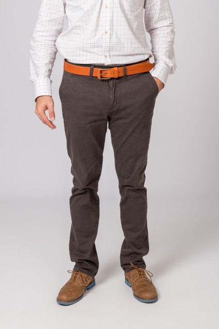 Homem com calças castanhas escuras, cinto castanho alaranjado e sapatos castanhos claros, em fundo cinza