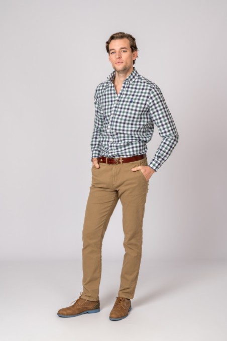 Homem com camisa xadrez azul e branca, calças e sapatos castanhos em fundo cinzento claro.