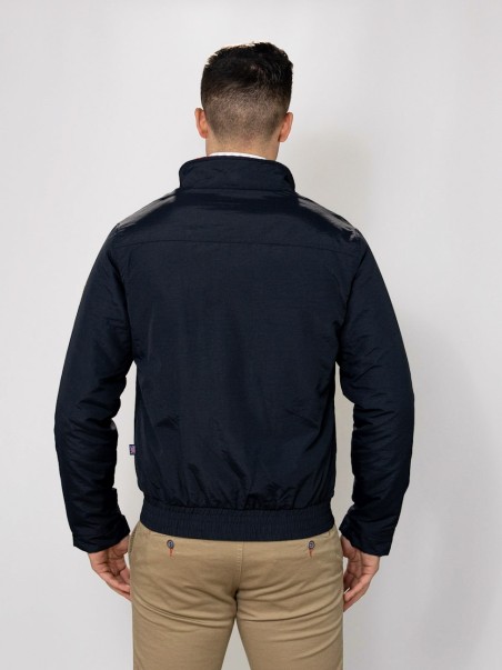 Casaco preto com gola alta e detalhe brilhoso nos ombros visto por trás