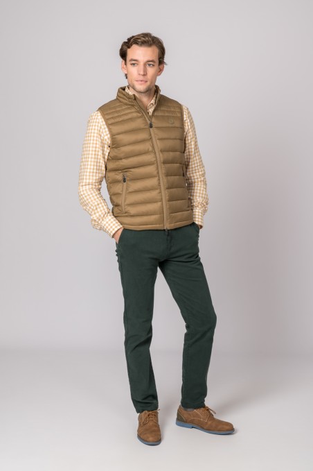 Homem com colete castanho, camisa bege às riscas, calças verdes escuras e sapatos castanhos