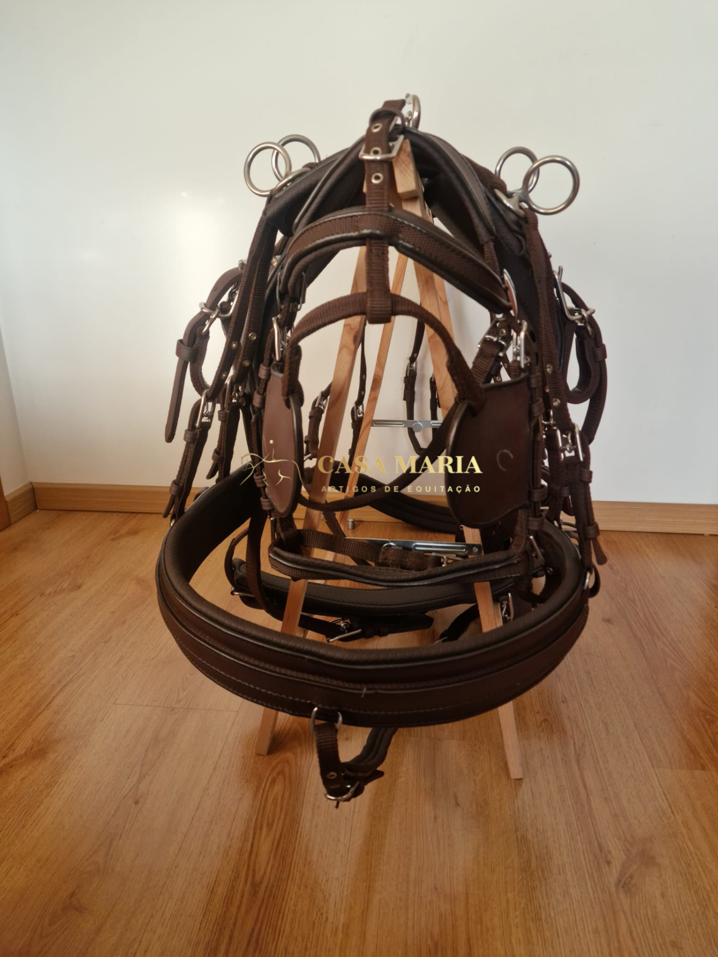 Freio em pele castanha com detalhes metálicos sobre estrutura de madeira com chão e parede claros.