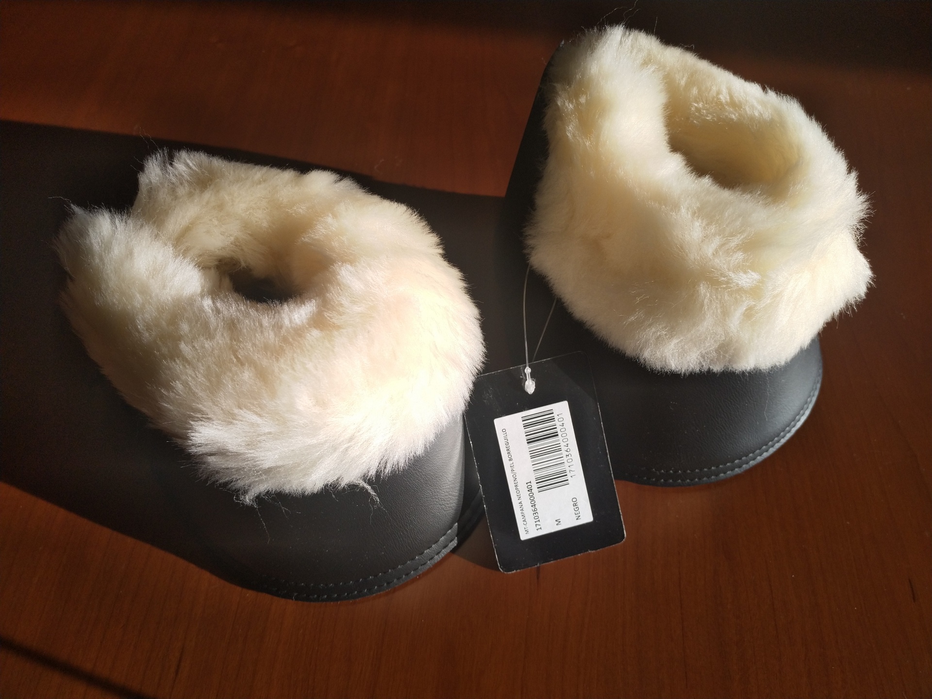 Polainas pretas com pelo branco e etiqueta com código de barras