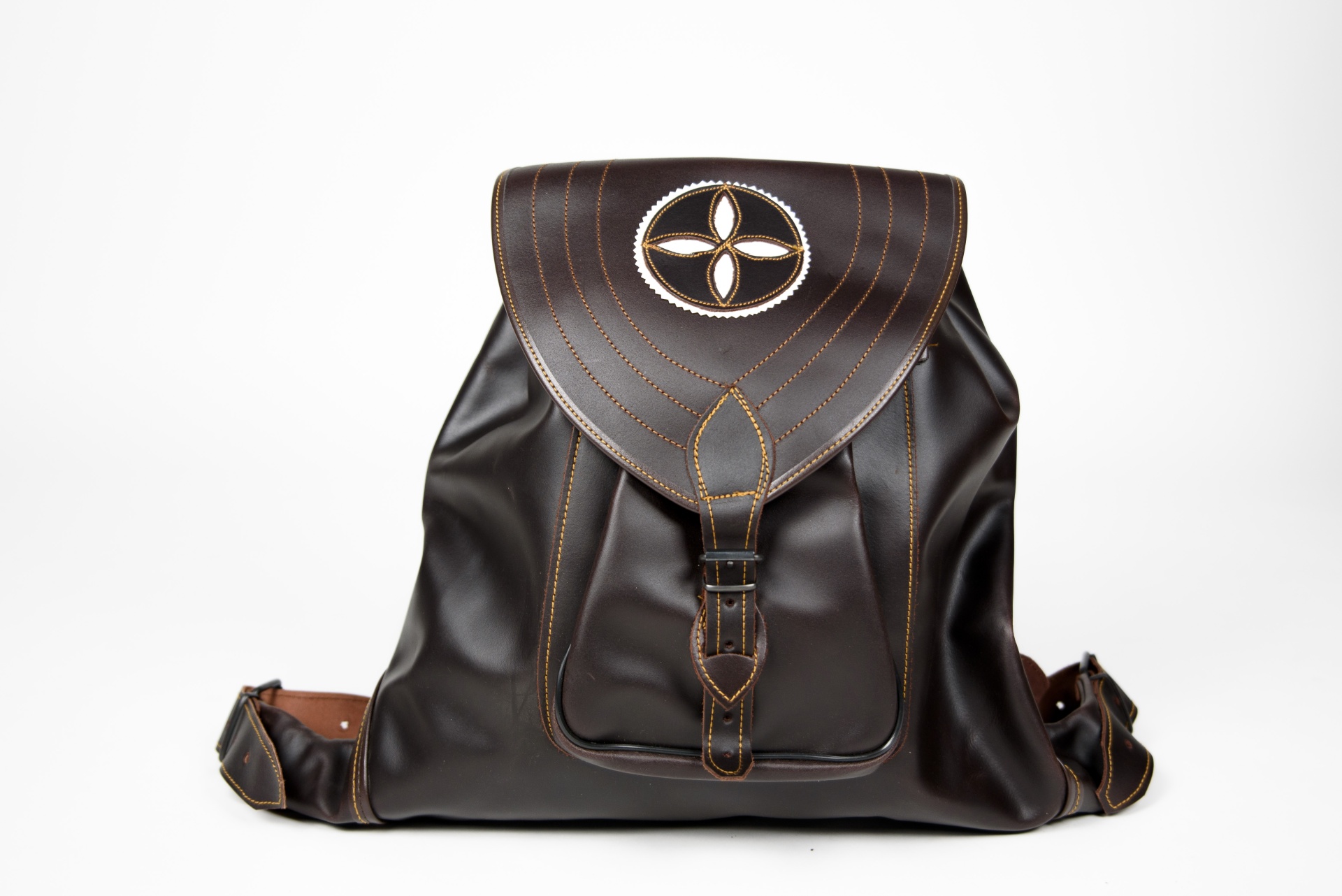 Mochila de pele castanha escura com fecho e símbolo decorativo.