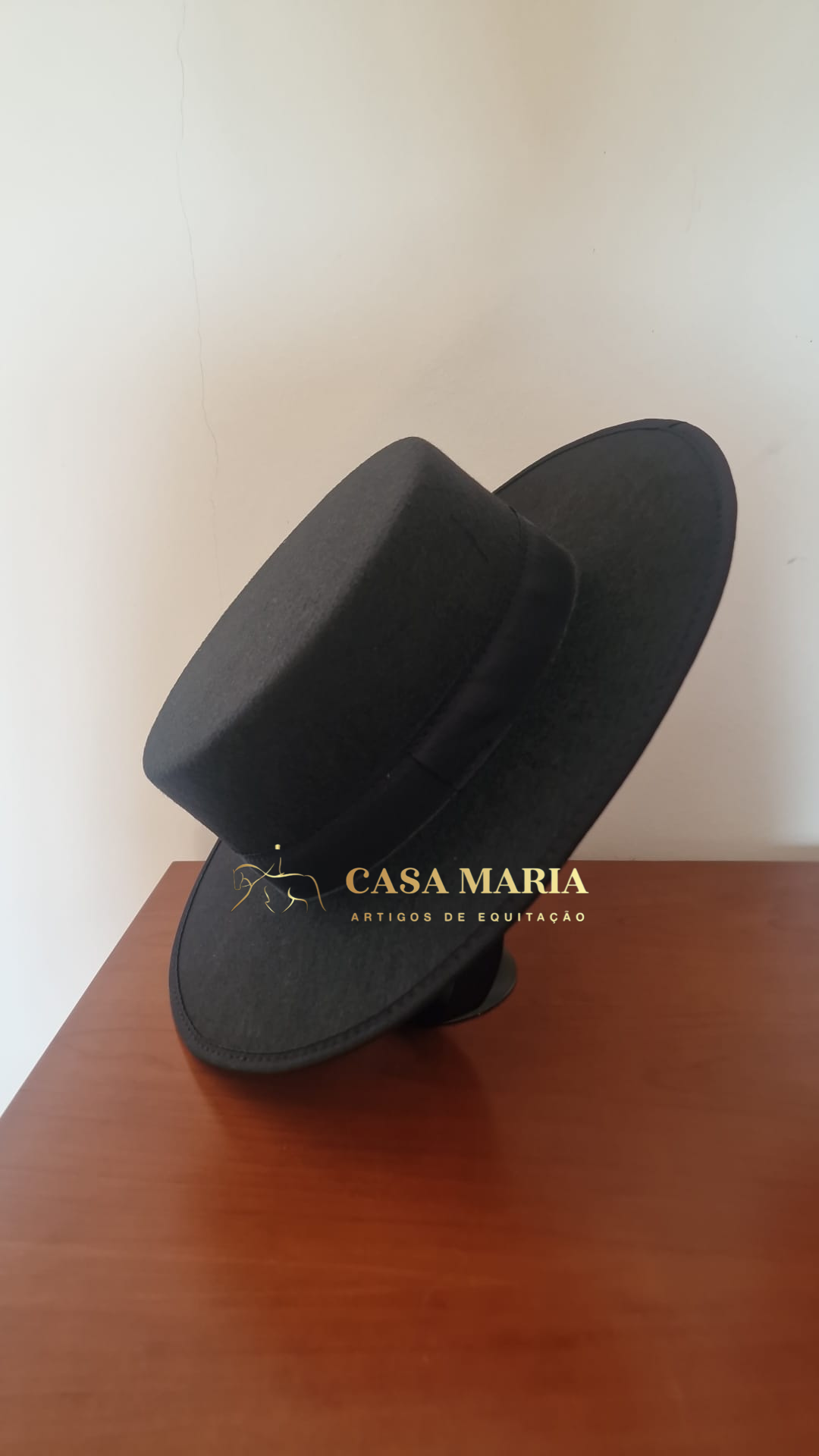 Chapéu preto com aba larga e fita preta sobre mesa de madeira