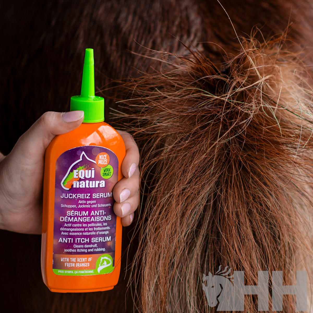 Frasco laranja de sérum anti-comichão Equi natura com tampa verde junto a pelo castanho grosso