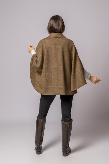 Mulher de costas com capa castanha xadrez, calças pretas e botas altas castanhas