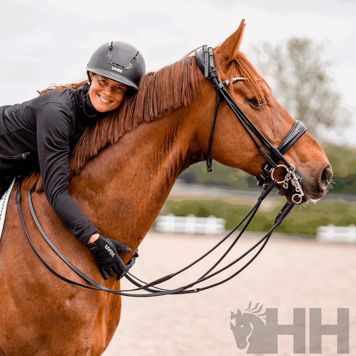Mulher vestida com capacete e luvas pretas montando cavalo castanho ao ar livre