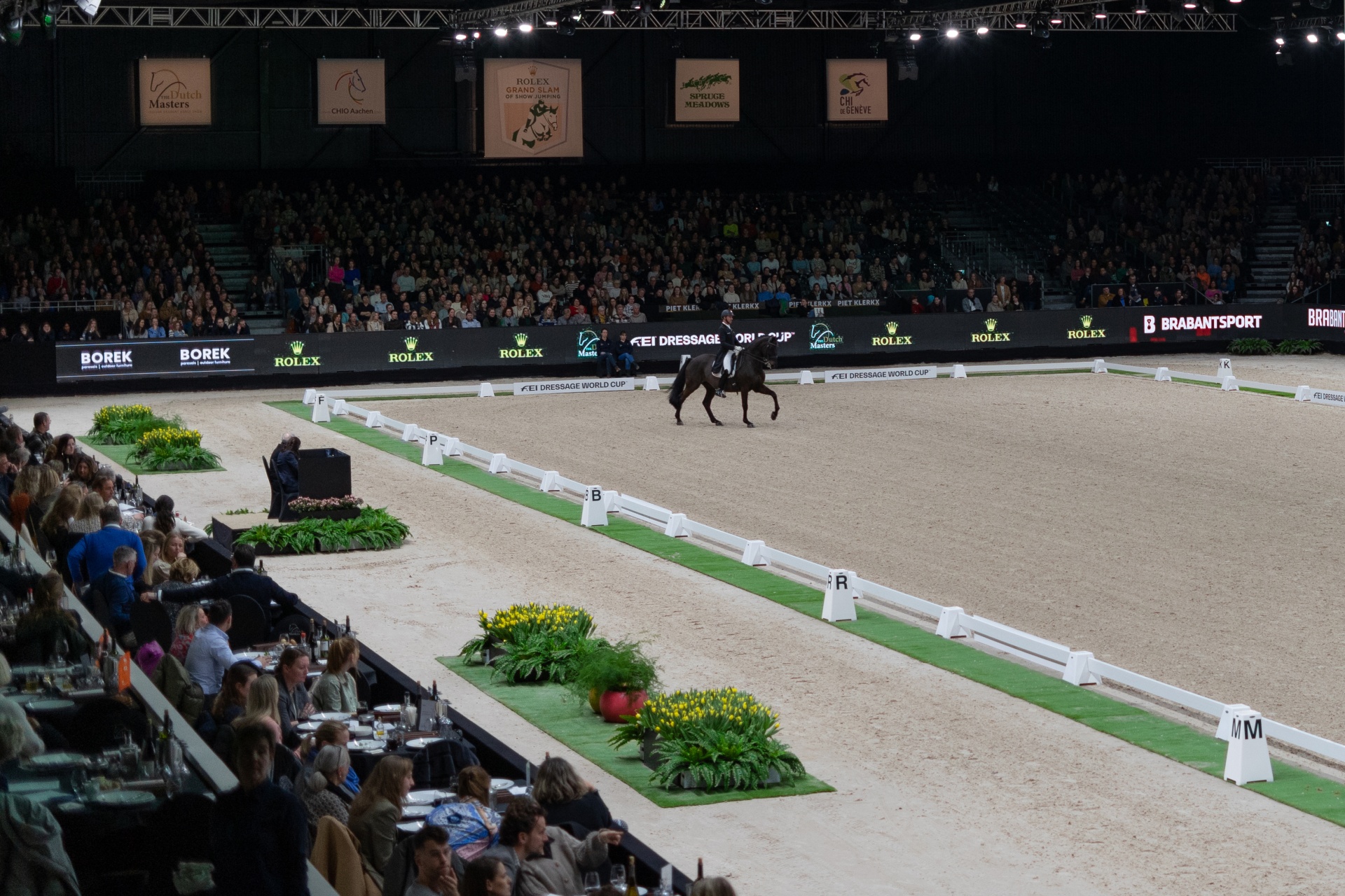 Arena de equitação coberta com cavaleiro e cavalo e público nas bancadas