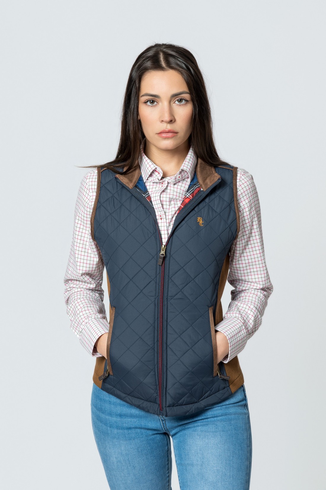Mulher com colete azul e camisa xadrez em fundo cinza