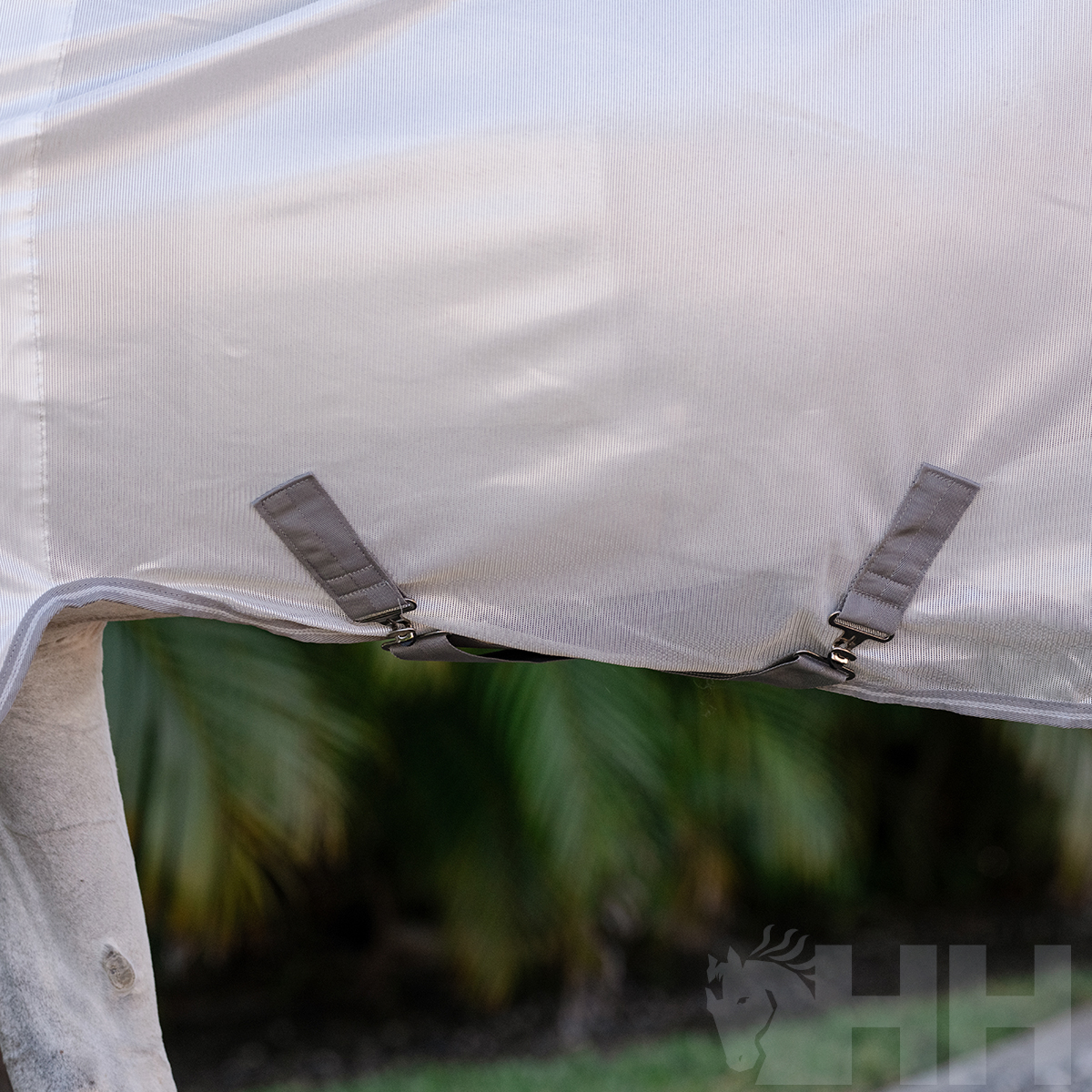 Tenda ou toldo branco com fivelas metálicas e vegetação ao fundo