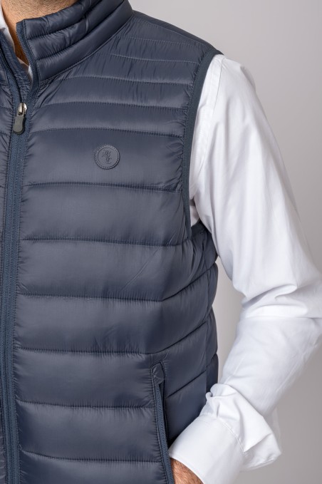 Colete masculino acolchoado azul escuro usado sobre camisa branca