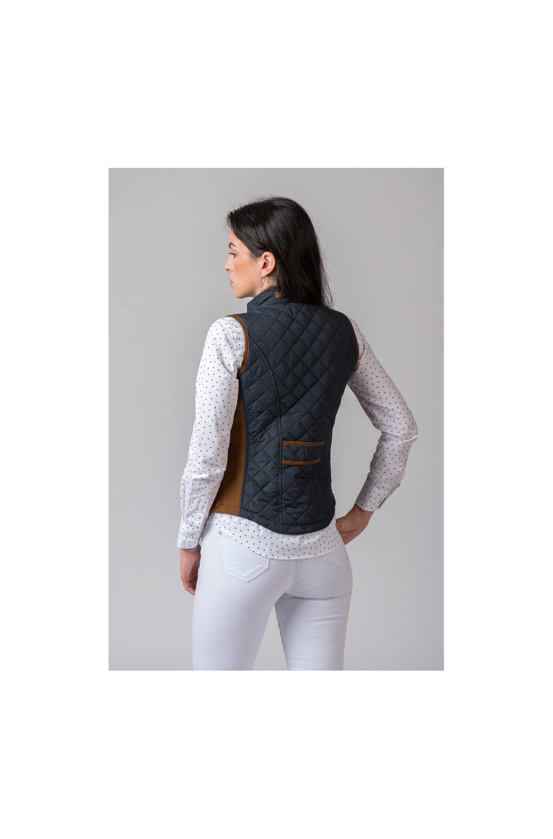 Colete azul escuro acolchoado com detalhes castanhos num ambiente neutro