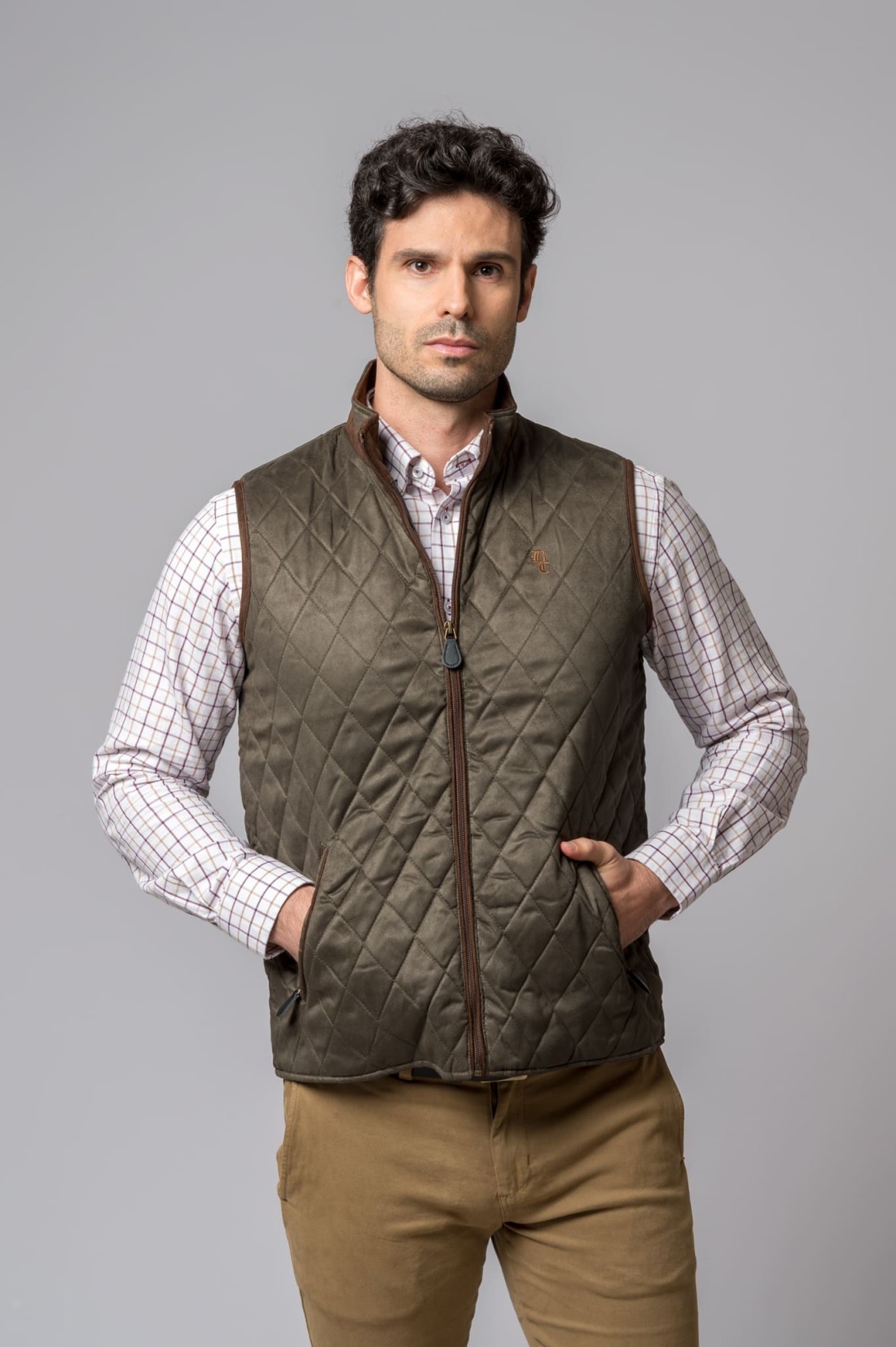 Homem com colete acolchoado verde-oliva e camisa de riscas