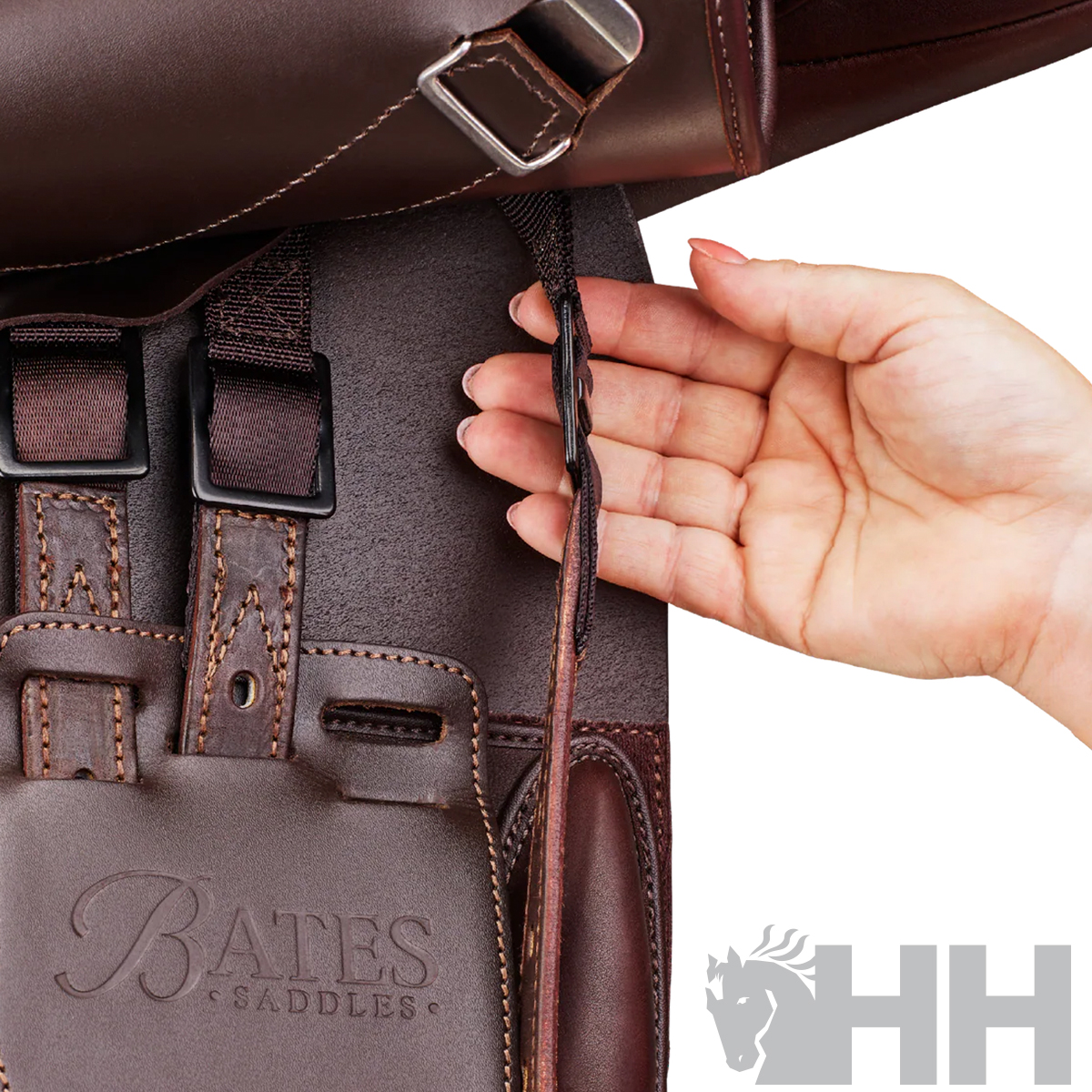 Sela de cavalo de couro castanho com marca Bates Saddles e mão segurando tira ajustável