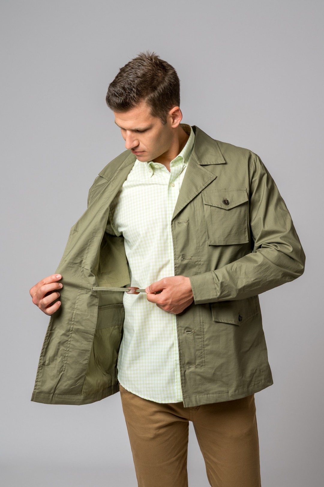 Homem com jaqueta verde-oliva e camisa branca aos quadrados verdes