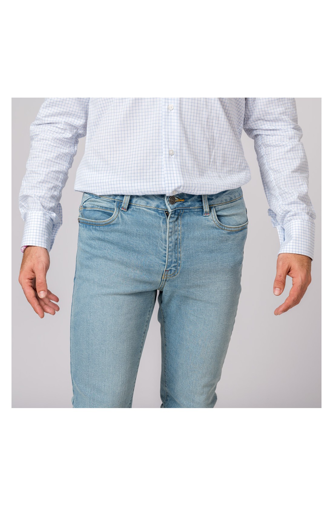 Homem veste camisa branca com padrão xadrez azul claro e calças de ganga azul claro