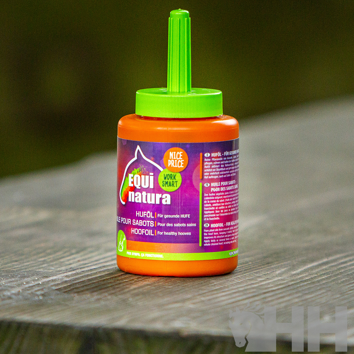 Frasco laranja com tampa verde e rótulo roxo de óleo para cascos de cavalos sobre mesa de madeira cinzenta